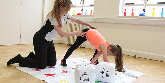 Young child using twister style game to stretch with therapist.