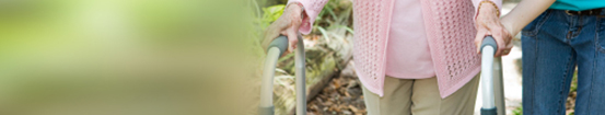 Therapist aids elderly patient with walking aid.