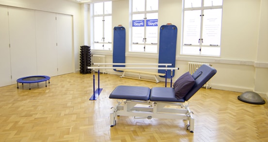 Interior shot of Manchester OT clinic with therapy bed and walking bars plus trampoline.