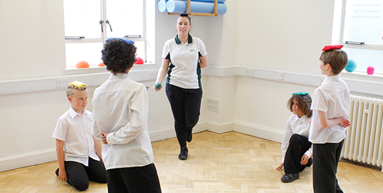 Group of children put bean bags on their head and try to balance during ManchesterOT session.