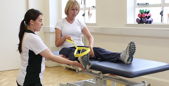 ManchesterOT patient gets help stretching using resistant bands with her therapist.